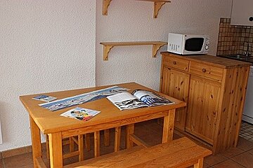 A wooden table with a magazine on it next to a microwave