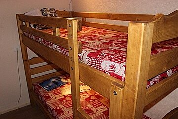 A bunk bed with a red and white blanket on it