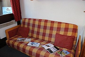 A couch with a plaid blanket sits in a living room