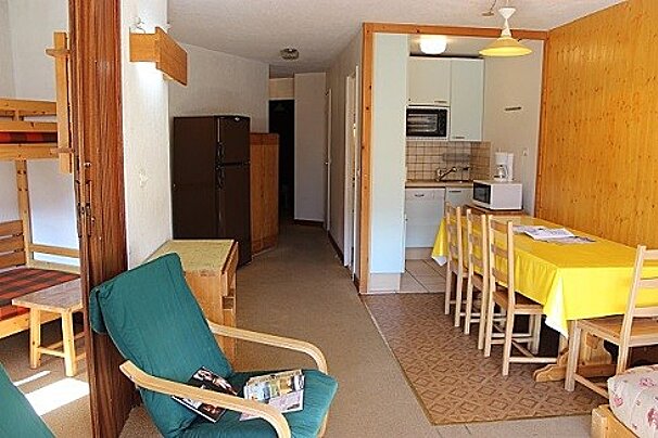 A living room with a chair and a table with a yellow table cloth