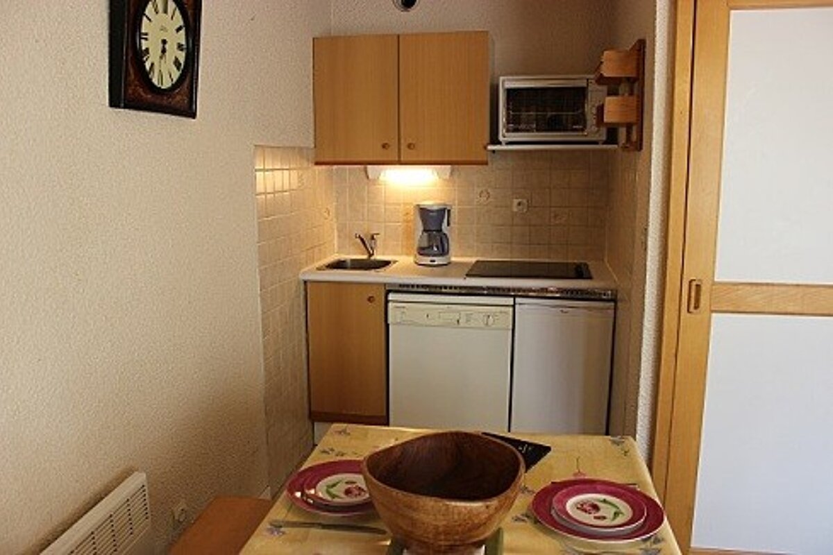 A small kitchen with a clock on the wall above it
