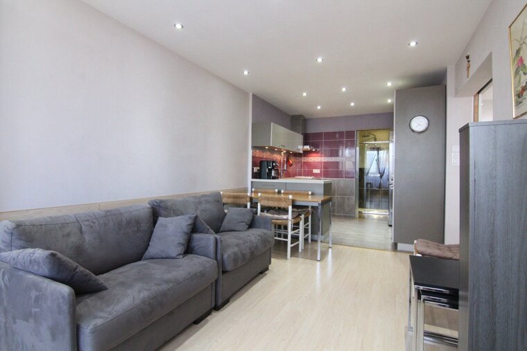 A living room with a couch and chairs and a clock on the wall