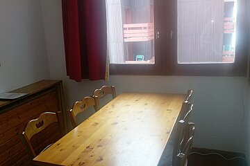 A wooden table and chairs in front of a window