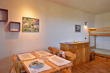 A picture of flowers hangs above a wooden table