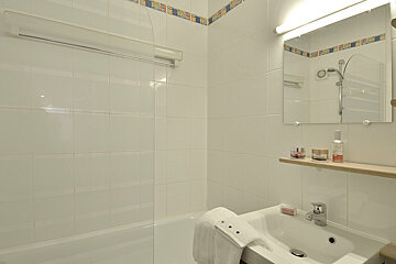 A bathroom with white tiles and a sink