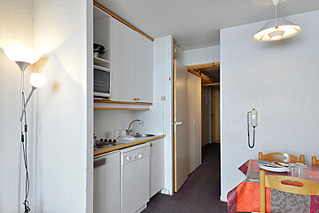 A kitchen with a table and chairs and a phone on the wall