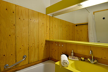A bathroom with wood paneling and a yellow sink