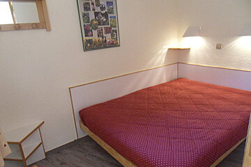 A bed with a red polka dot blanket in a bedroom