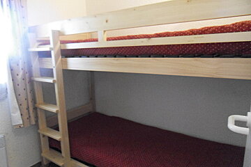 A bunk bed with red polka dot sheets and a ladder