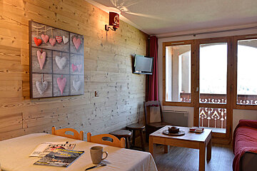 A living room with a table and chairs and a painting of hearts on the wall