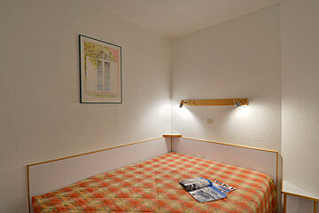 A bed with a plaid blanket and a magazine on it