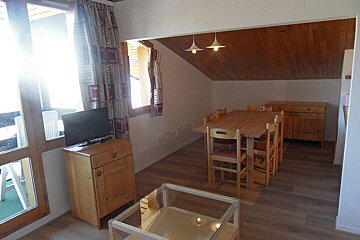 A living room with a table and chairs and a tv