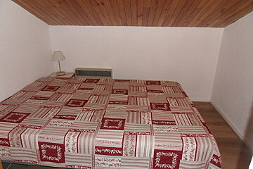 A bed with a red and white blanket that says ' fleurs ' on it