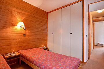 A bedroom with two beds and a lamp on the wall