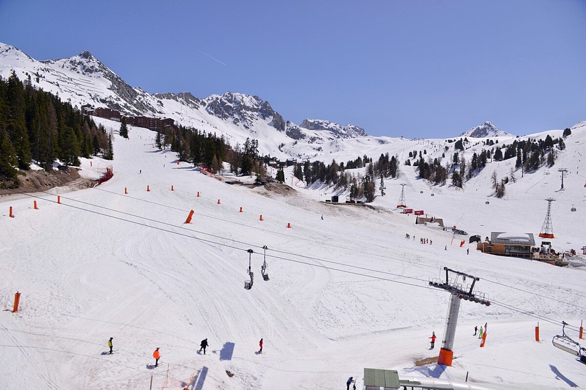 A ski lift is going down a snow covered slope