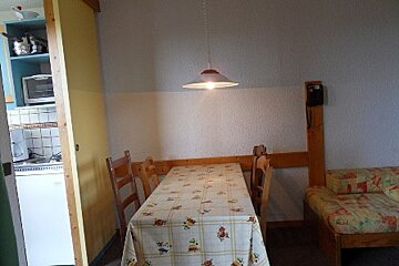 A kitchen with a table and chairs and a light hanging from the ceiling