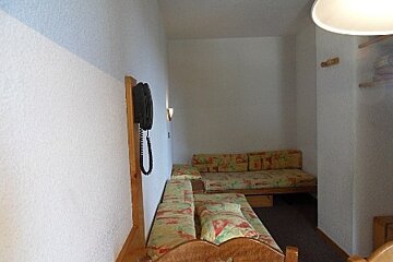 A phone hanging on a wall next to a couch