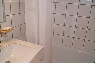 A bathroom with white tiles and a sink