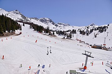 A ski lift is going down a snow covered slope