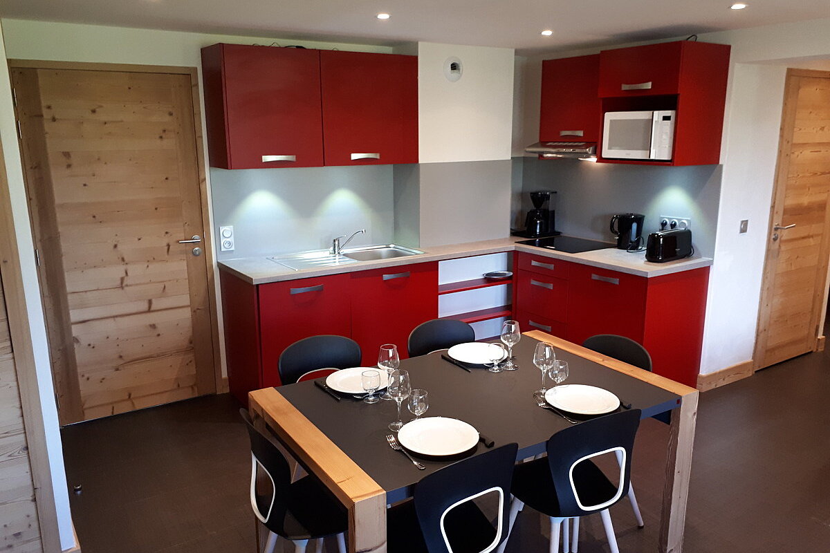 A kitchen with red cabinets and a black table