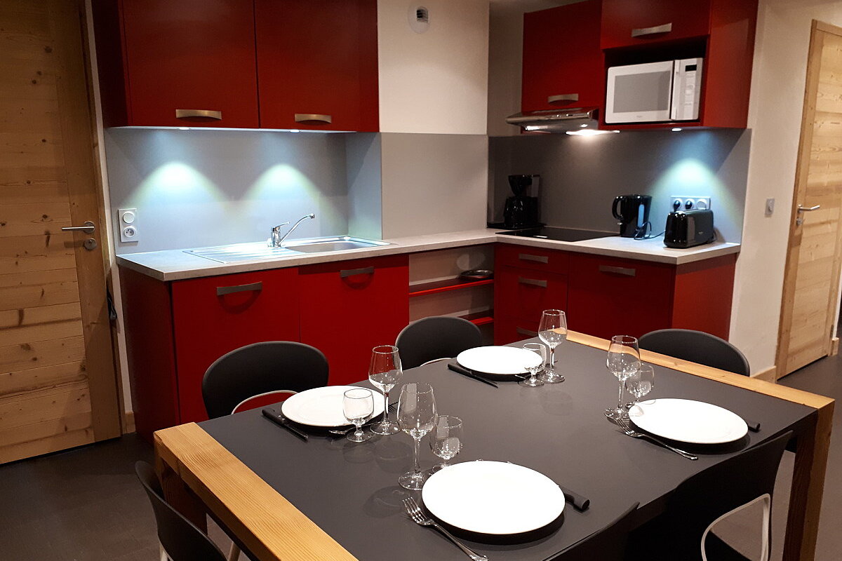 A kitchen with red cabinets and a table with plates and glasses on it
