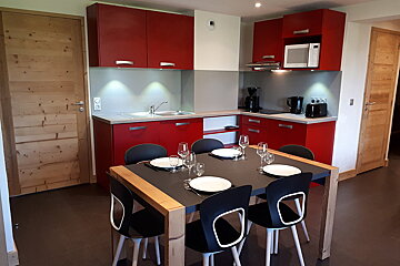 A kitchen with red cabinets and a dining table
