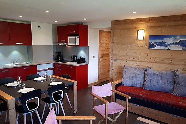 A kitchen with red cabinets and a picture of mountains on the wall