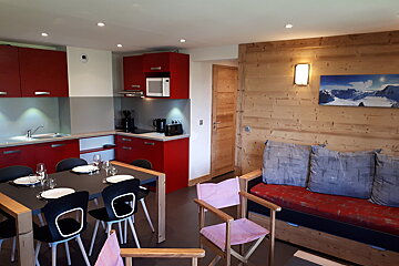 A kitchen with red cabinets and a picture of mountains on the wall
