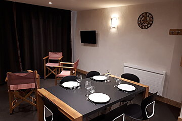 A clock with roman numerals on it hangs above a dining table