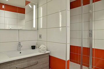 A bathroom with red and white tiles and a sink