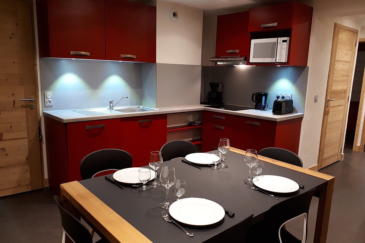 A kitchen with red cabinets and a table with plates and glasses on it