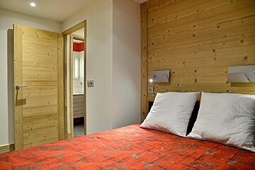 A bedroom with a wooden wall and a bed