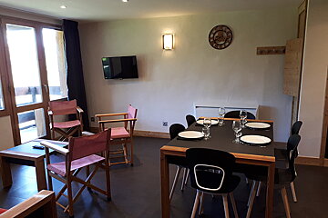 A living room with a table and chairs and a clock on the wall