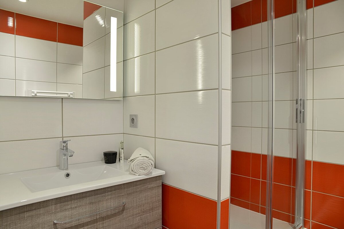 A bathroom with red and white tiles and a sink