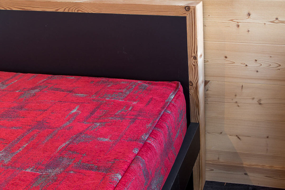 A bed with a red plaid blanket on it