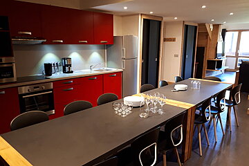 A kitchen with red cabinets and a long table