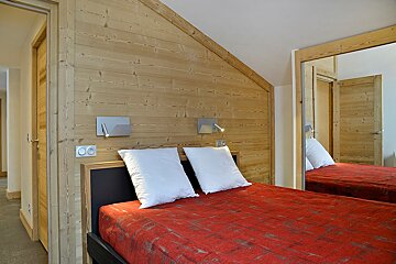 A bedroom with a red blanket and white pillows