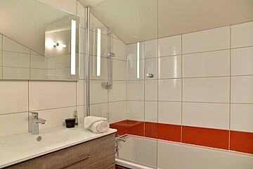 A bathroom with red and white tiles and a sink