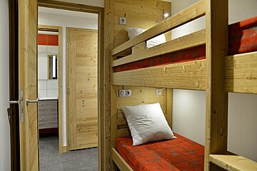 A bunk bed with a red blanket and white pillows