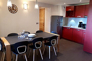 A kitchen with a table and chairs and a clock on the wall
