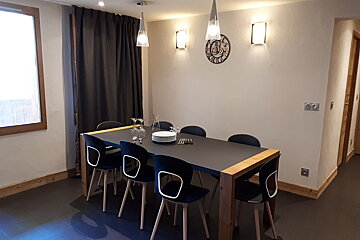 A clock on the wall above a dining table
