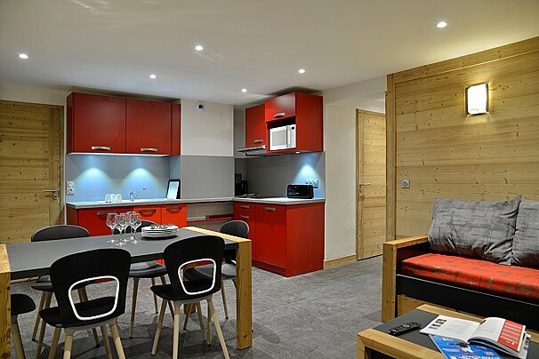 A living room with red cabinets and black chairs