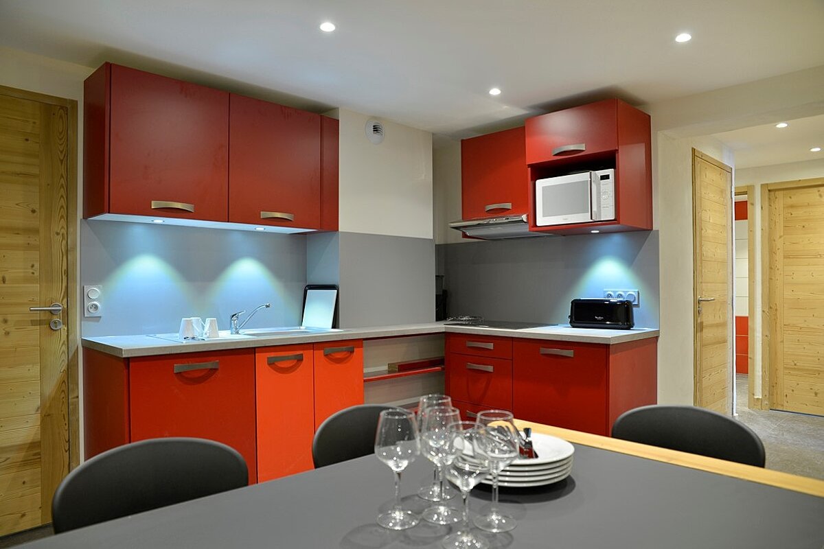 A kitchen with red cabinets and a microwave