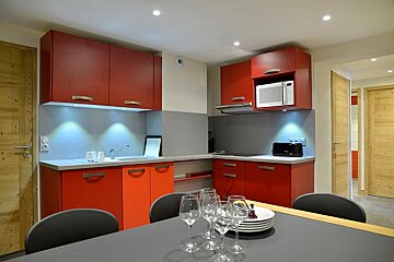 A kitchen with red cabinets and a microwave