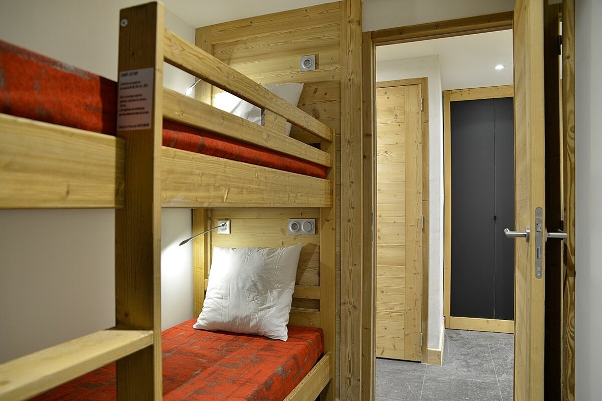 A bunk bed with a red blanket and white pillows
