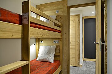 A bunk bed with a red blanket and white pillows