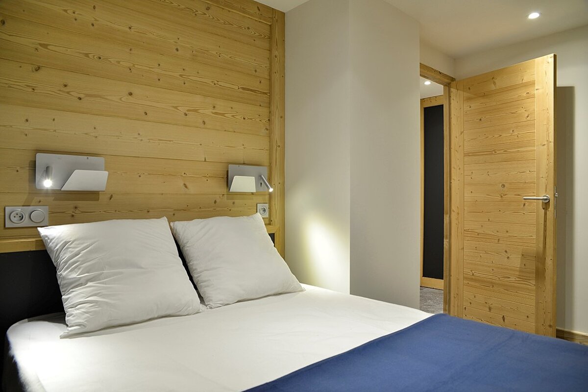 A bedroom with a wooden wall and a bed