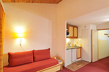 A living room with a red couch and red pillows