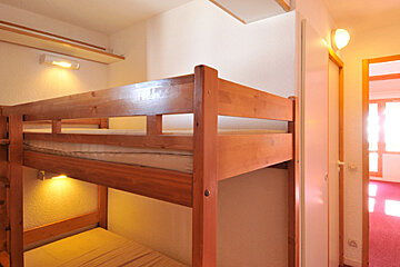 A bunk bed in a room with a light on the wall