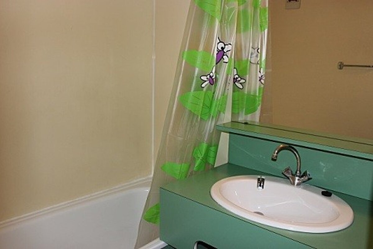 A bathroom with a green sink and a green shower curtain